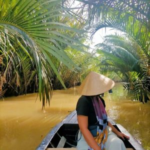 Tourist enjoying a peaceful boat ride on a small canal in Ben Tre Mekong Delta
