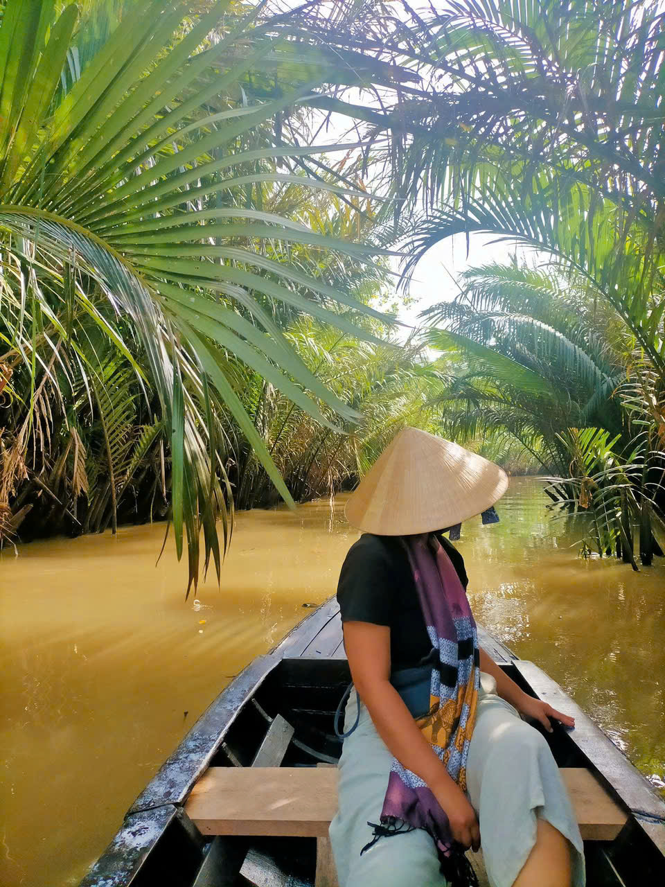 Tourist enjoying a peaceful boat ride on a small canal in Ben Tre Mekong Delta